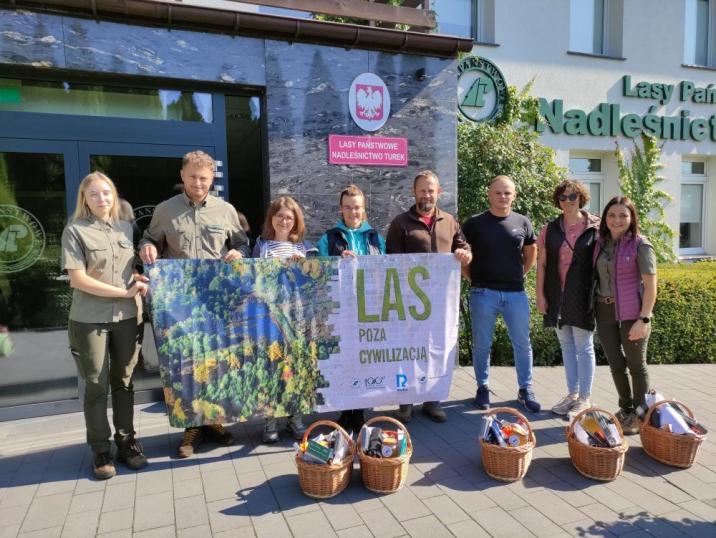 Zdjęcie&#x20;przedstawia&#x20;uczestników&#x20;IX&#x20;edycji&#x20;Lasu&#x20;poza&#x20;Cywilizacją&#x20;w&#x20;towarzystwie&#x20;leśników&#x2c;&#x20;trzymających&#x20;banner&#x20;i&#x20;stojących&#x20;pod&#x20;siedzibą&#x20;Nadleśnictwa&#x20;Turek&#x2e;&#x20;Fot&#x2e;&#x20;Archiwum&#x20;RDLP&#x20;w&#x20;Poznaniu